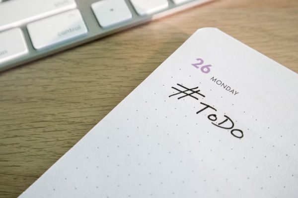 Close-up of a to-do list next to a computer keyboard on a desk.