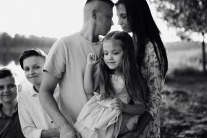 A serene black and white portrait of a family standing by a lake.
