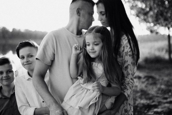 A serene black and white portrait of a family standing by a lake.